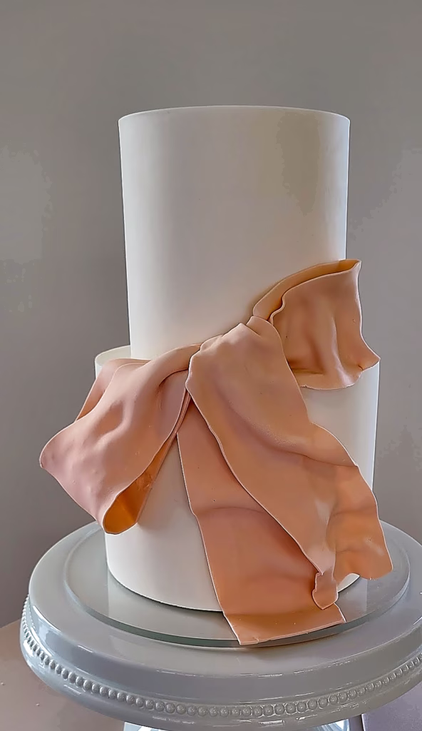 White fondant wedding cake with blush pink bow drape
