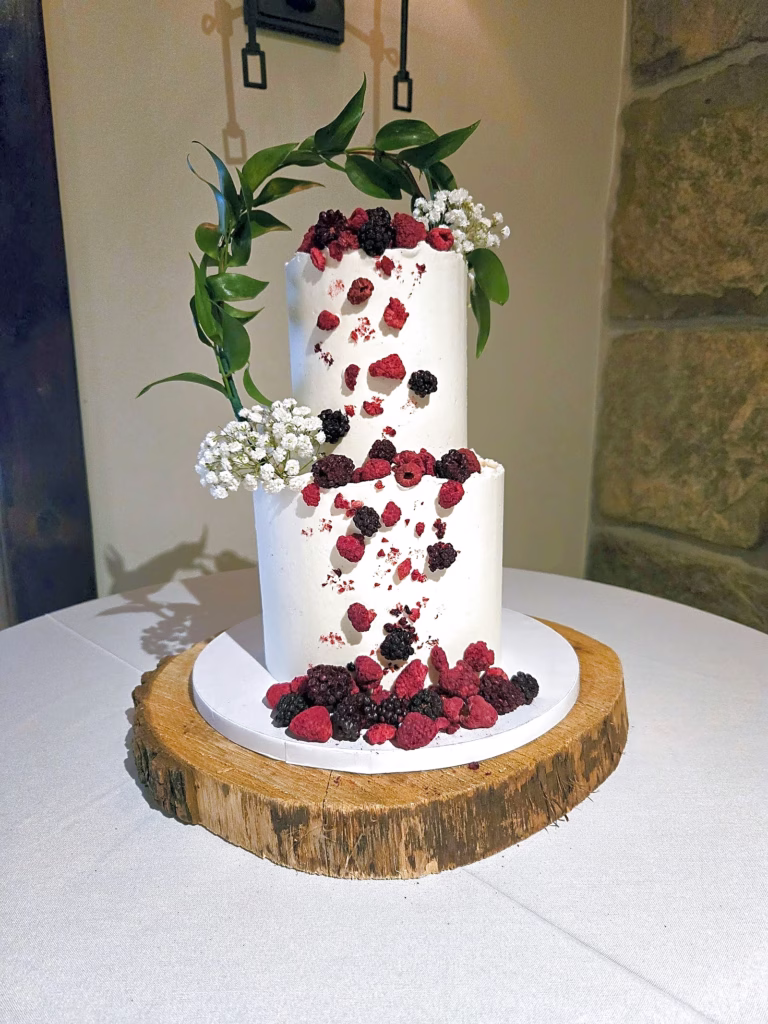 Rustic wedding cake with fresh berries on a wood slice stand