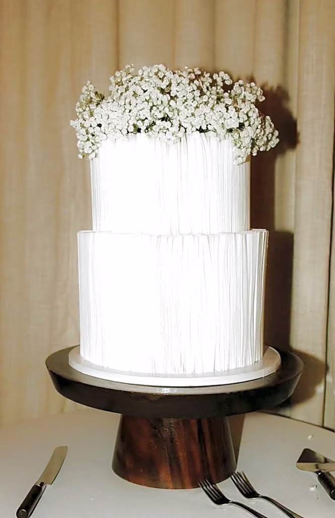 Textured buttercream wedding cake with baby's breath on a wood stand