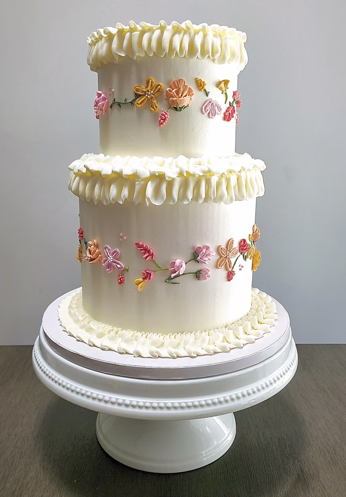 Three tier vintage piped wedding cake with peach blossom garlands